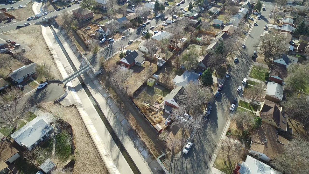 Aerial view of homes, streets, and a concrete drainage channel.