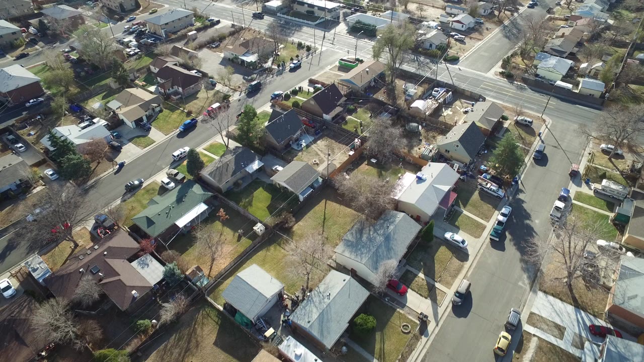 Overhead frame from Westminster, Colorado showing single-family homes, fenced yards, leafless trees, intersecting residential streets, parked cars, and no visible people.