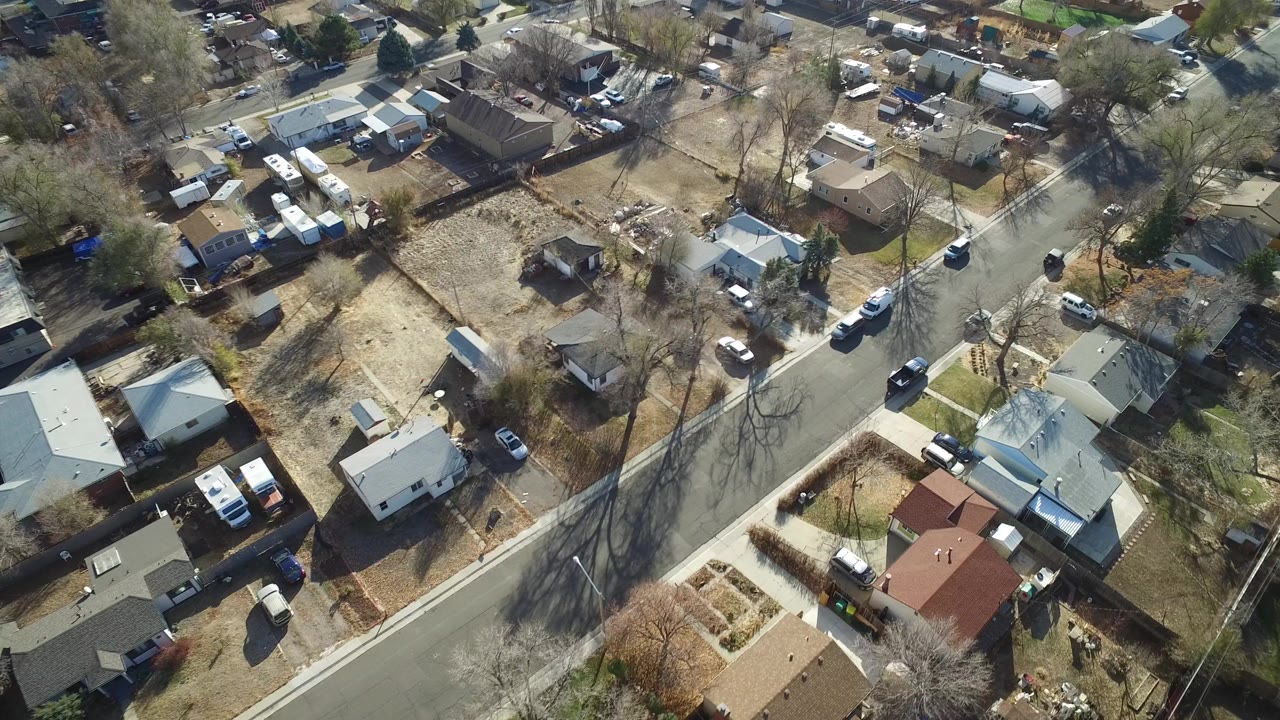 Aerial view of a residential street with small houses and parked vehicles
