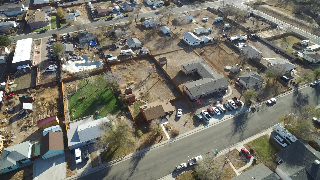 Aerial view of suburban streets, homes, fenced yards, and parked cars.