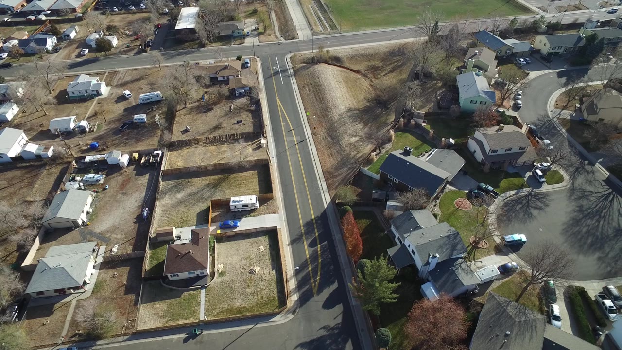 Drone view of houses around a cul-de-sac near a larger road.