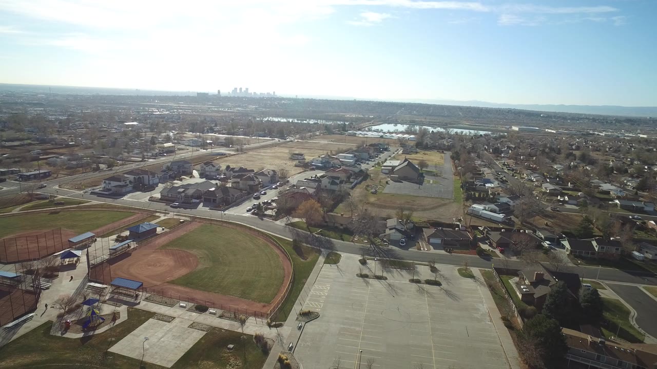 Aerial view of a baseball field beside parking lots and suburban streets.