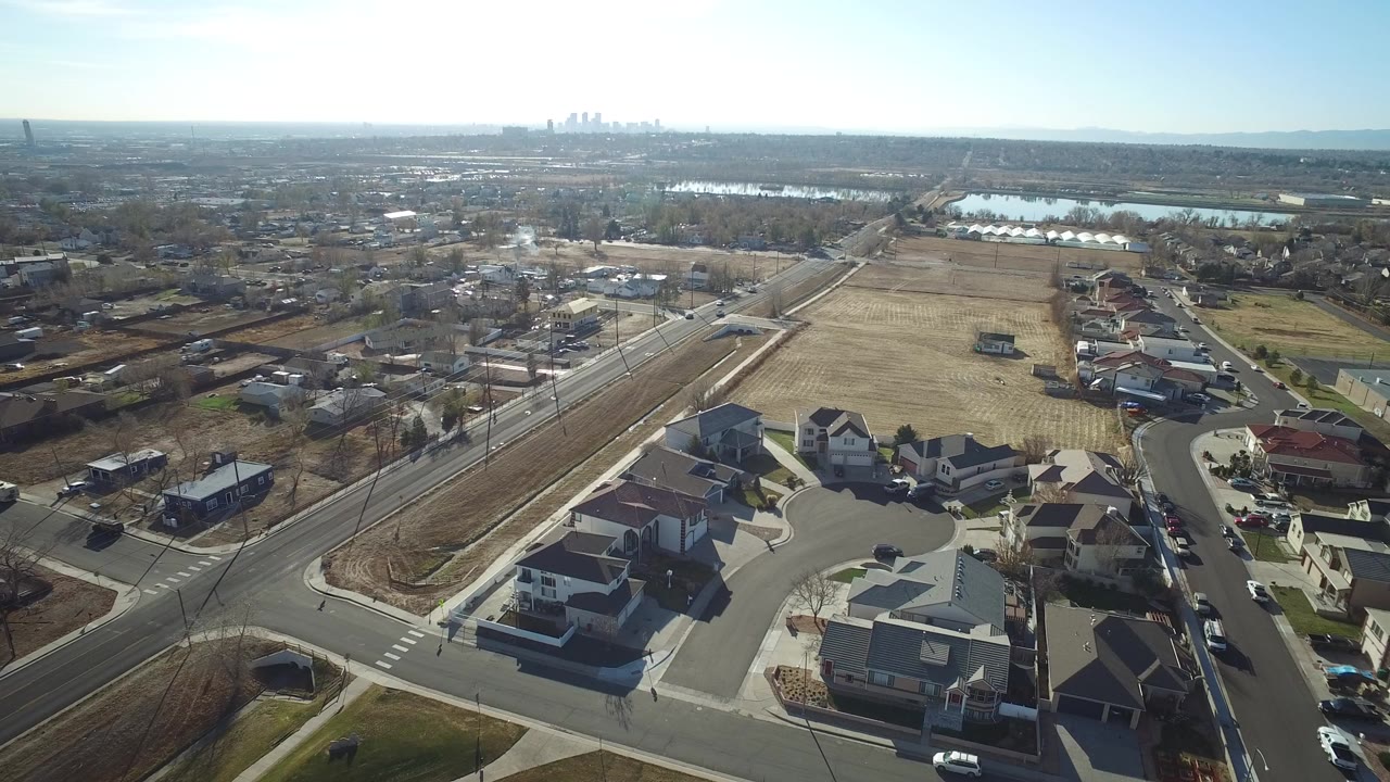 Aerial view of suburban homes, roads, fields, and distant skyline