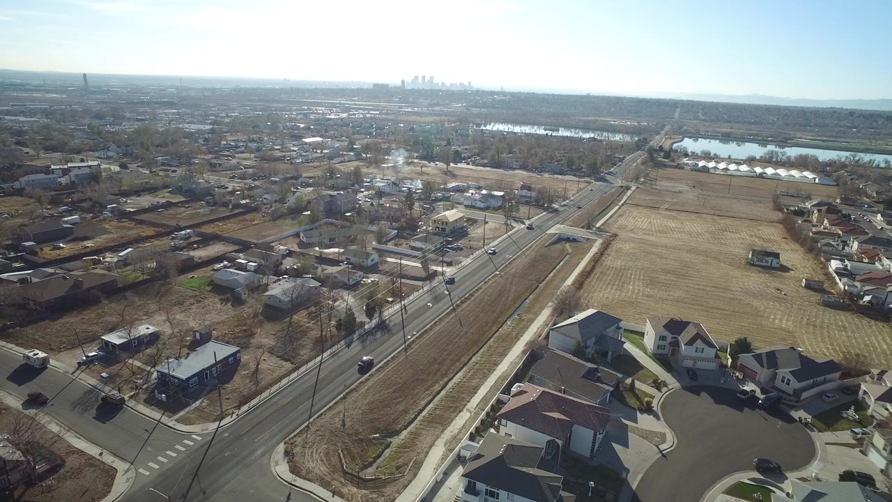 Aerial view of suburban road, houses, fields, and distant skyline