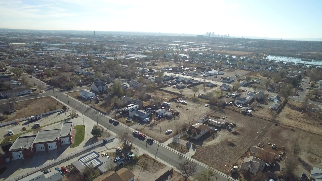 Aerial view of suburban roads, houses, trailers, and distant skyline.