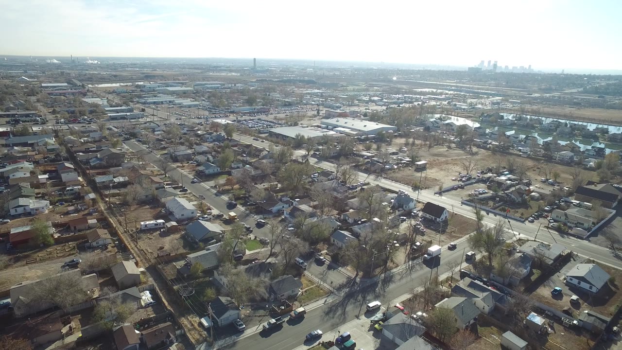 Suburban aerial with roads, houses, warehouses, and skyline haze