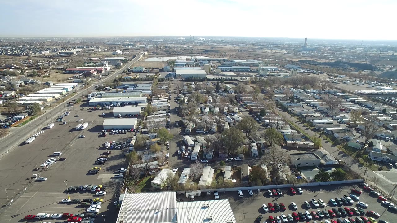 Aerial view over a parking lot, industrial buildings, and nearby homes.