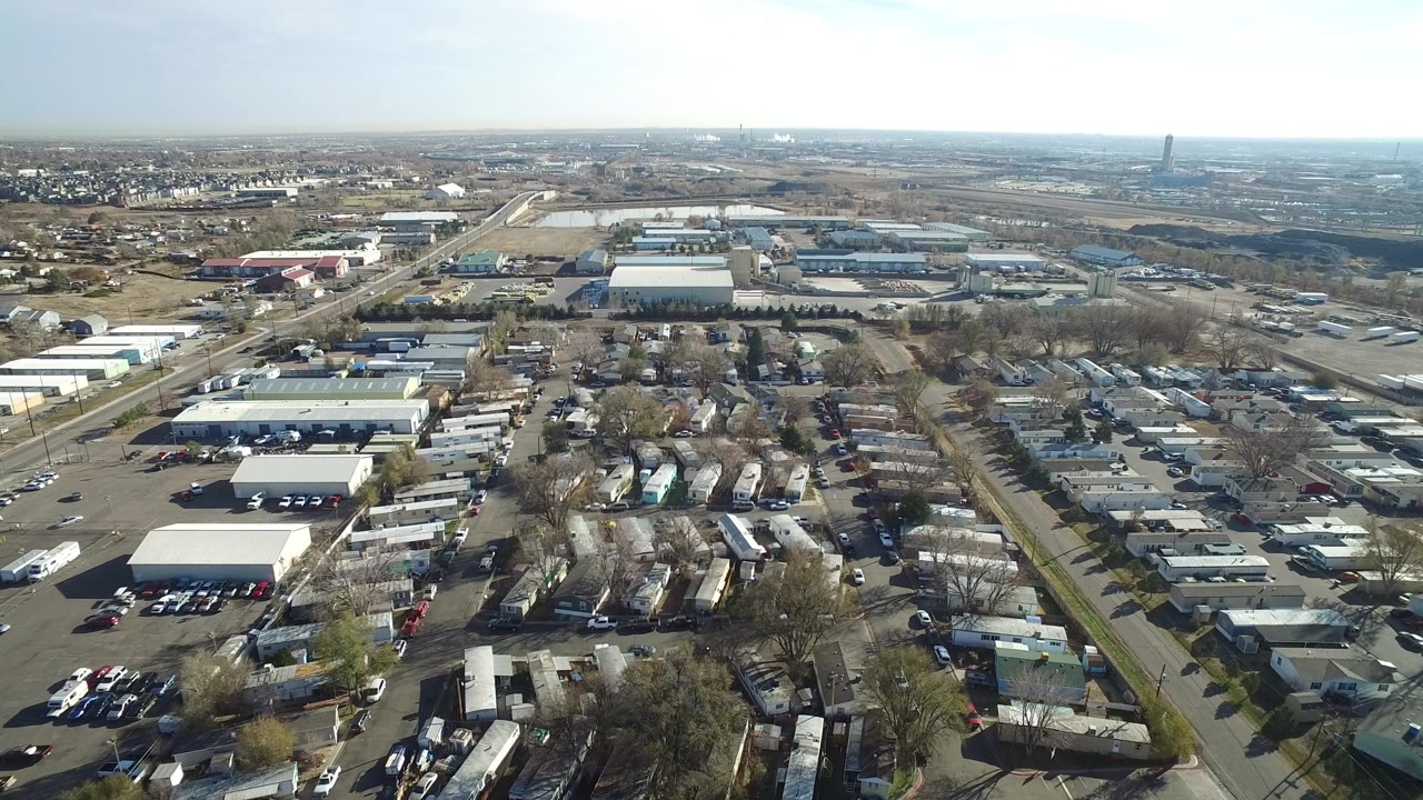 Aerial view over warehouses, roads, trailers, and distant suburbs