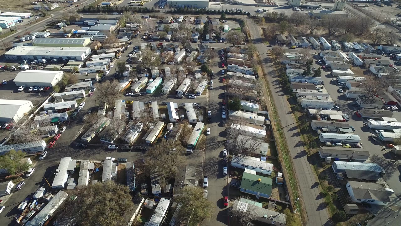 Aerial view of mobile homes, roads, trees, and industrial buildings.