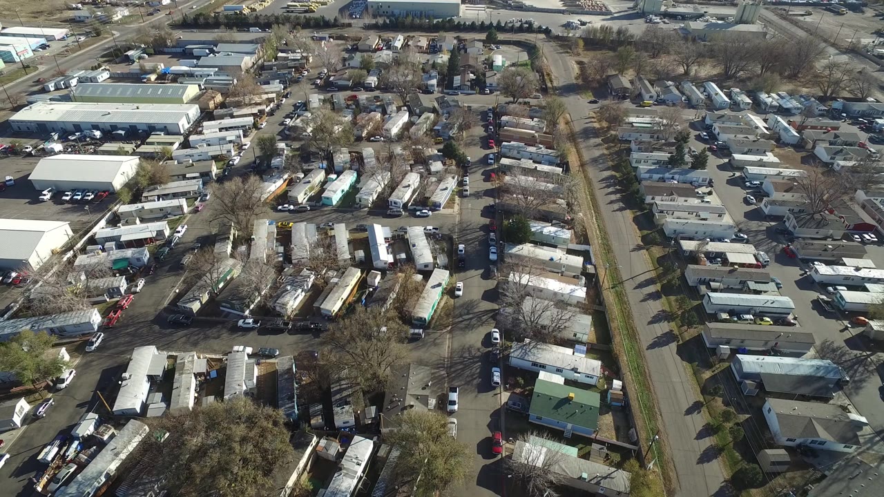 Westminster, Colorado aerial frame with trailer rows clustered around narrow streets, cars in driveways, larger white-roofed buildings at the top, and no visible people.