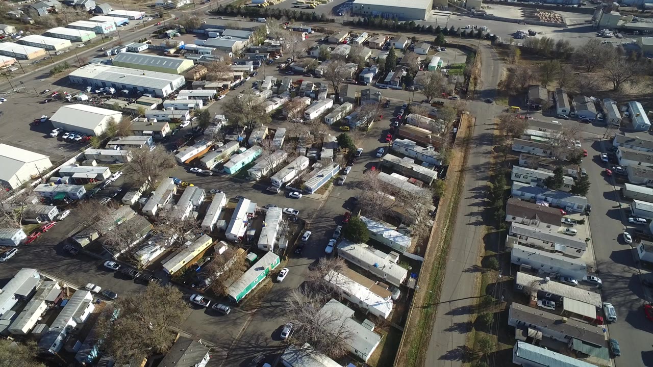 Aerial view over residential lots, streets, parked cars, and warehouse buildings.