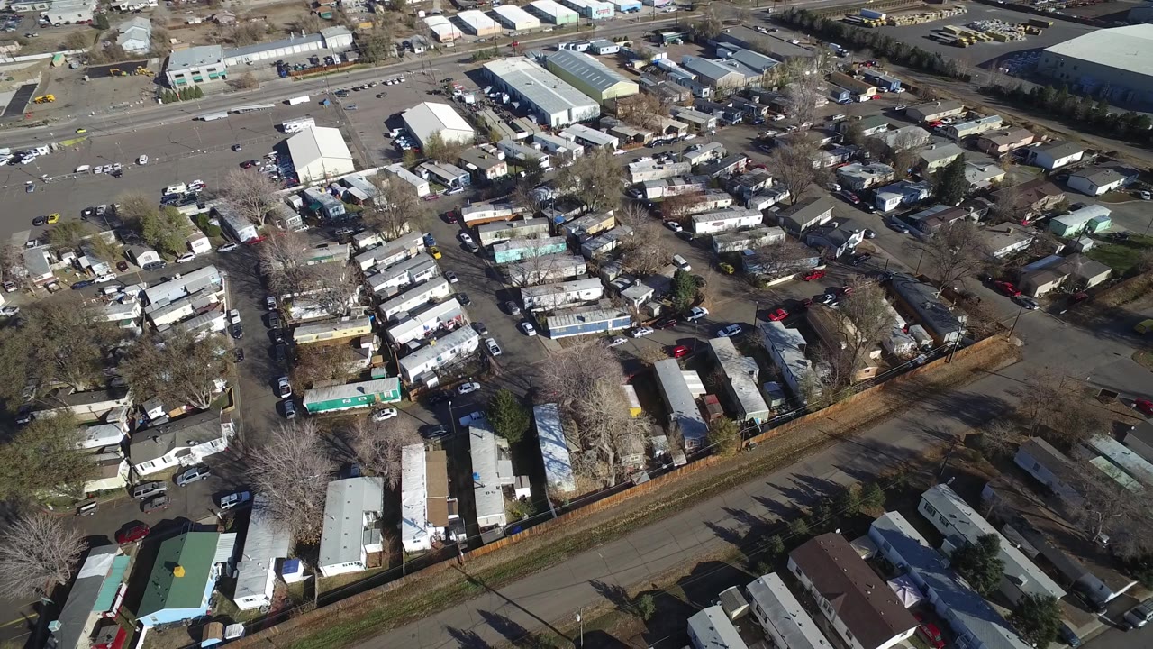 Oblique aerial over mobile home lots, streets, and warehouse roofs.
