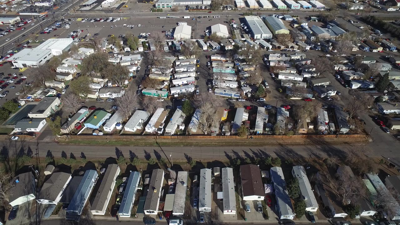 Aerial view of modular homes, streets, trees, and commercial buildings.