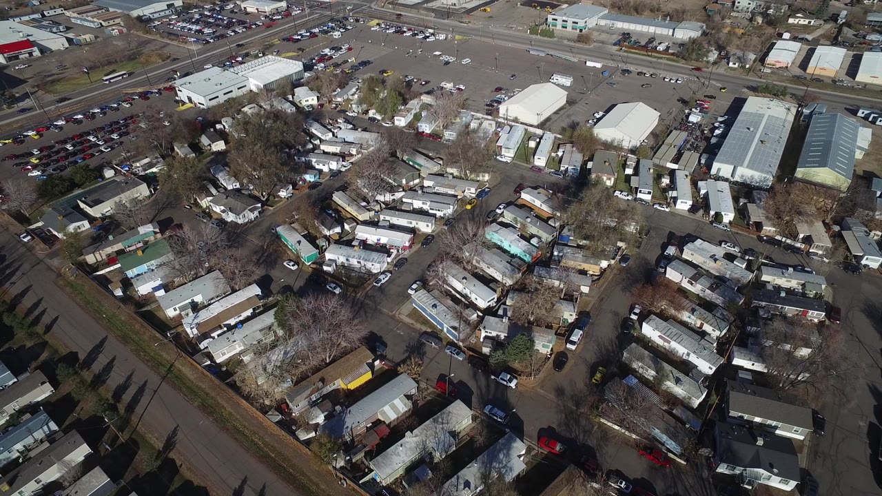 Drone-style overhead of roads, homes, cars, and industrial lots.