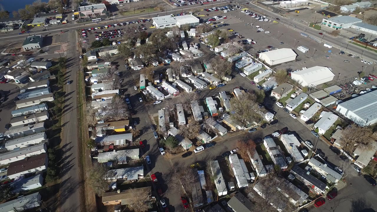 High aerial view over Westminster, Colorado showing mobile homes, local streets, parked cars, parking lots, bare trees, and low buildings, with no visible people.