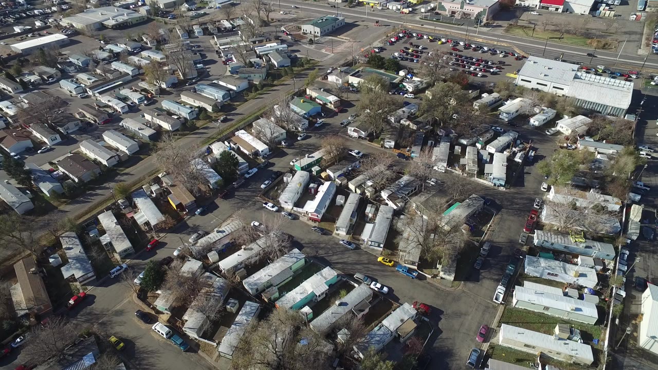 Aerial view of trailers, parked vehicles, roads, and bare trees.
