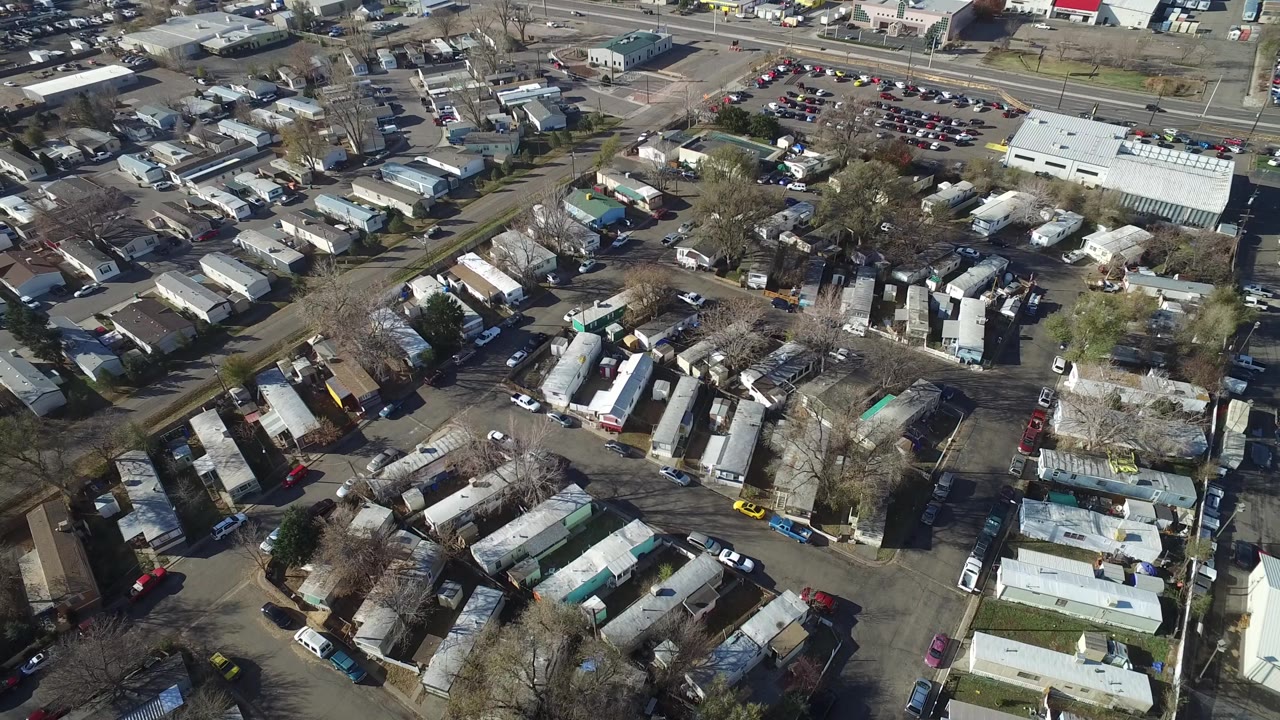 Aerial view in Westminster, Colorado with trailer rows in the lower frame, a larger light-roofed building near the upper right, parking lots, roads, and no visible people.