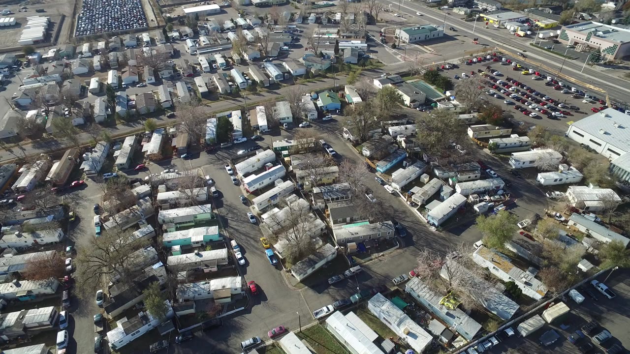 Aerial view of trailer rows, parked vehicles, trees, and roads.