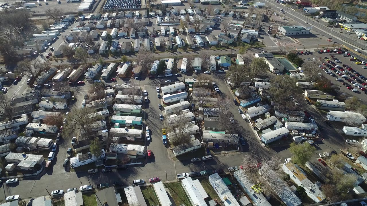 Aerial view in Westminster, Colorado showing dense rows of trailers or mobile homes, parked vehicles, internal roads, leafless trees, and no visible people at the start of the clip.