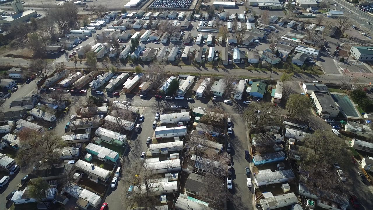Overhead view of a residential area with rows of small homes, roads, bare trees, and parked cars.