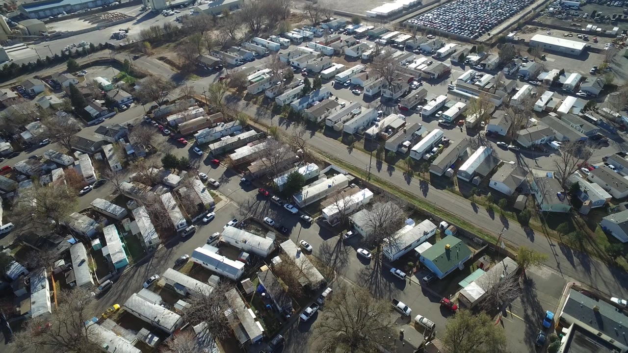 A slightly shifted aerial frame over Westminster, Colorado shows rows of trailer homes divided by a diagonal road, with cars along the lanes and no visible people.