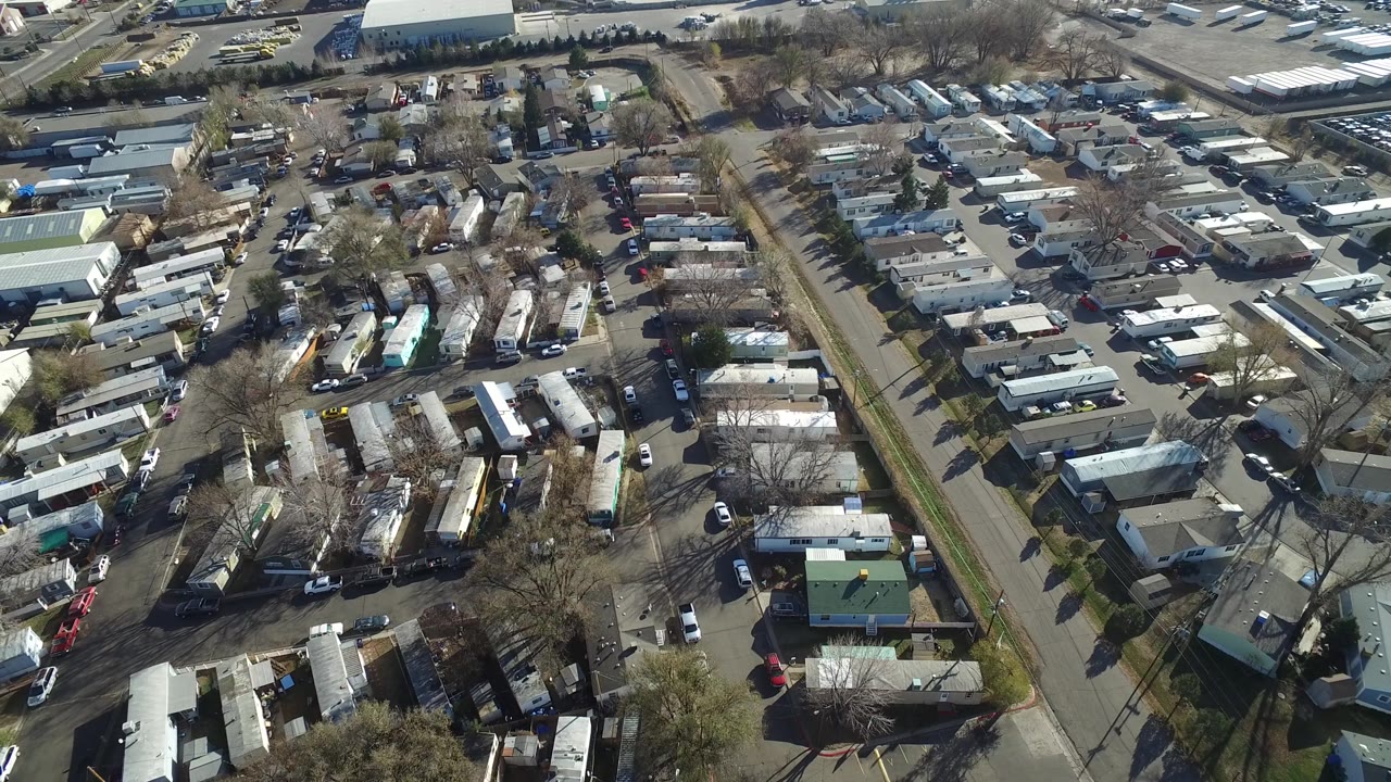 Aerial frame over Westminster, Colorado, with rows of small residences, a central road, parked cars, yard areas, and no visible people one second into the clip.