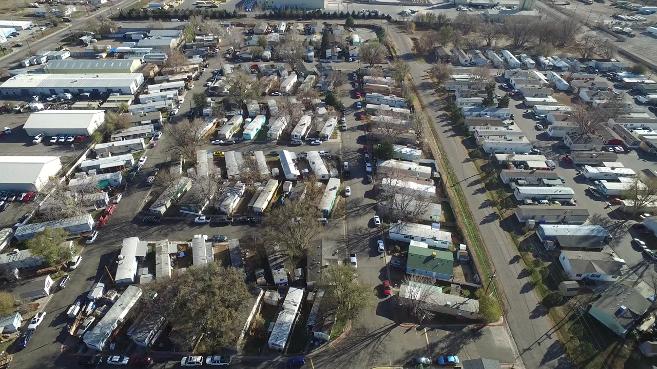 Aerial view of trailers, parked cars, roads, and low industrial buildings.