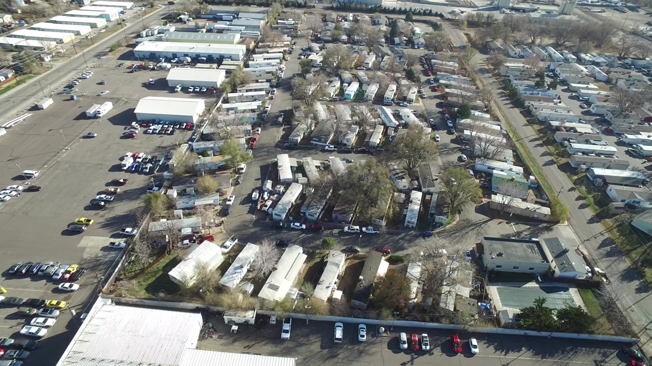 Overhead view of suburban roads, parking lots, low buildings, and homes.
