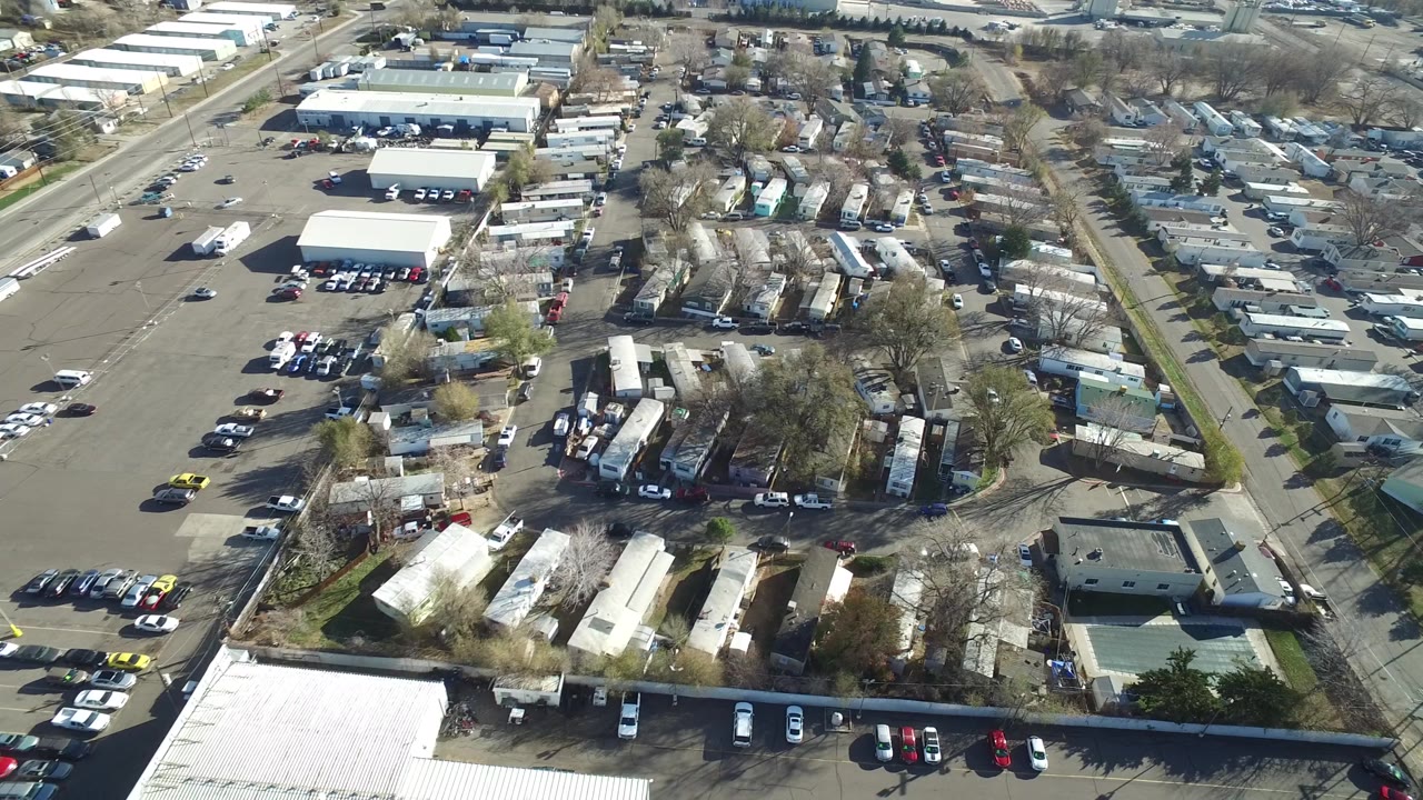 Overhead Westminster, Colorado frame with a wide parking area at left, low warehouse-like buildings at top, clustered residential structures near center, parked vehicles, and no visible people.