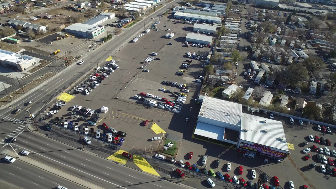 Aerial view of a busy intersection, parking lots, cars, and low commercial buildings.