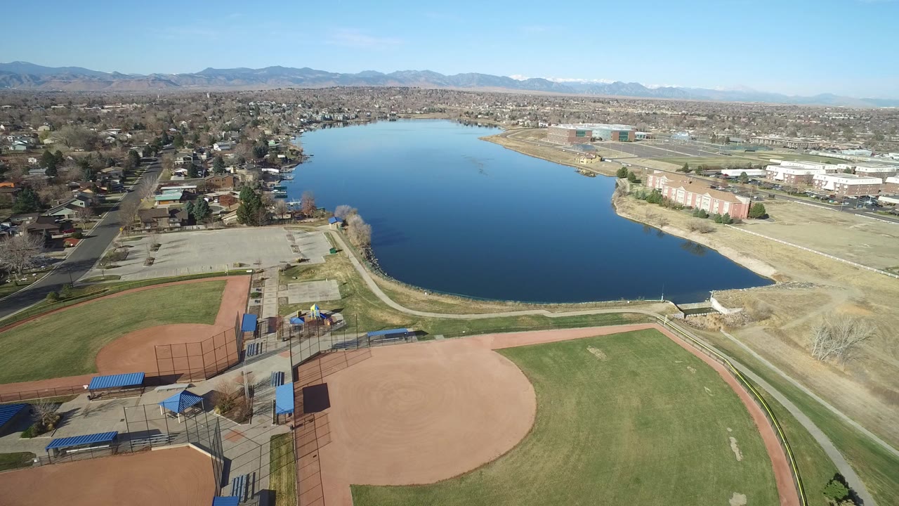 Aerial view of a blue lake beside baseball fields and suburban streets.