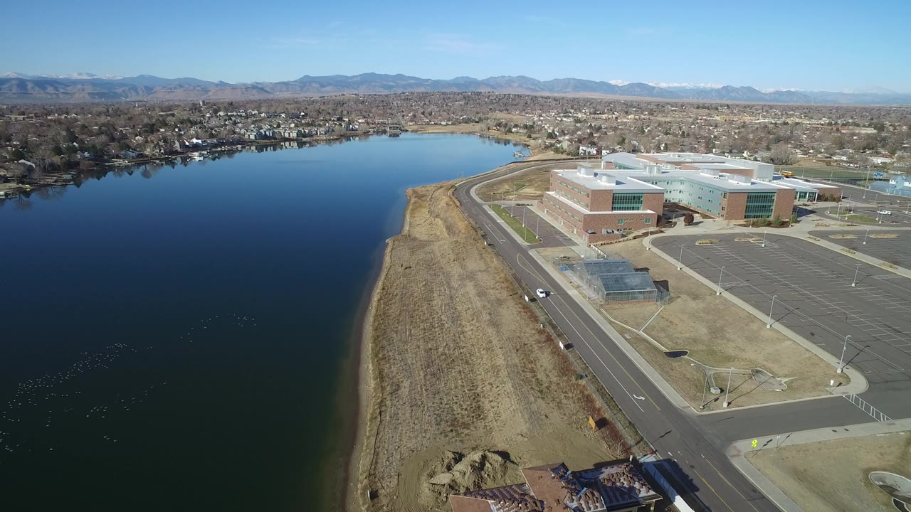 Aerial view of a lake beside a road and large modern buildings.