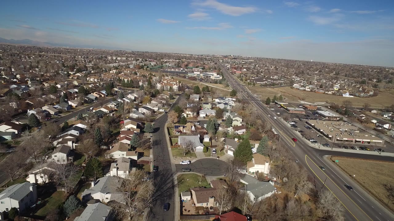 Aerial view of suburban homes beside a wide road under blue sky.