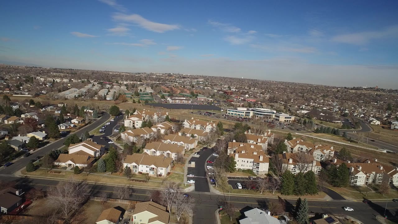Aerial view of suburban homes, roads, and a wide blue sky.