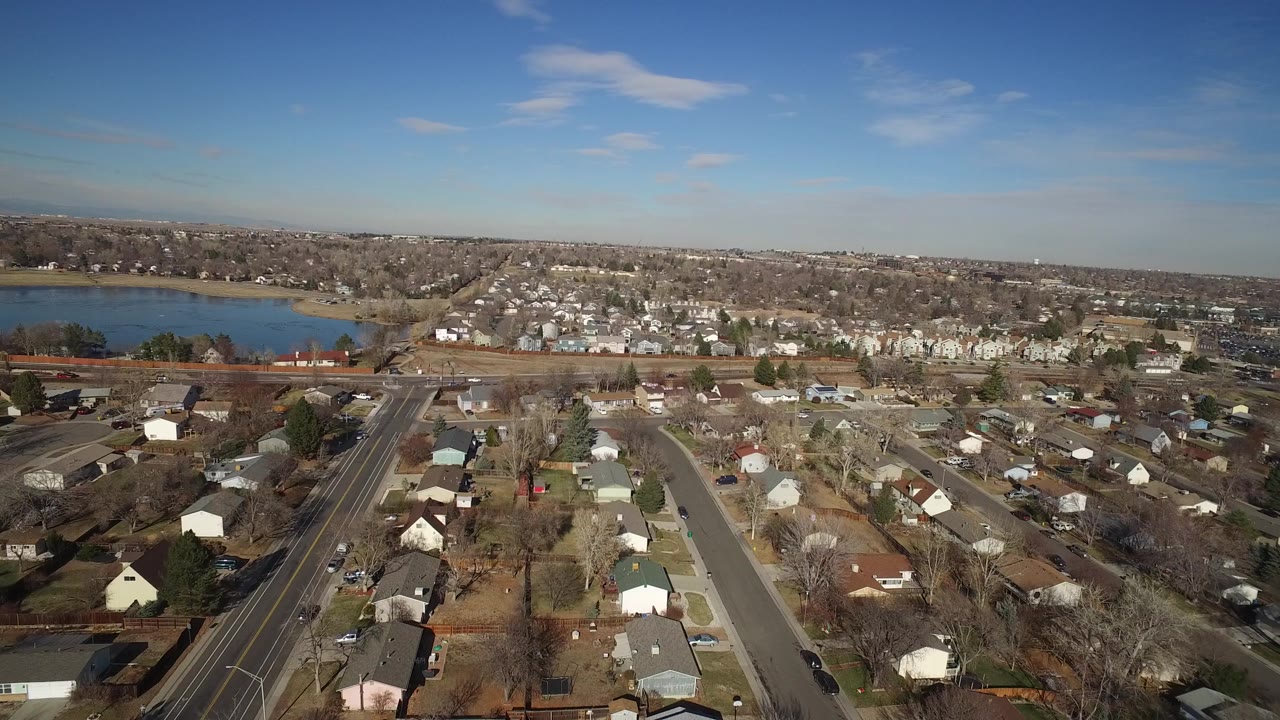 Aerial view of suburban homes and streets with a lake on the left.