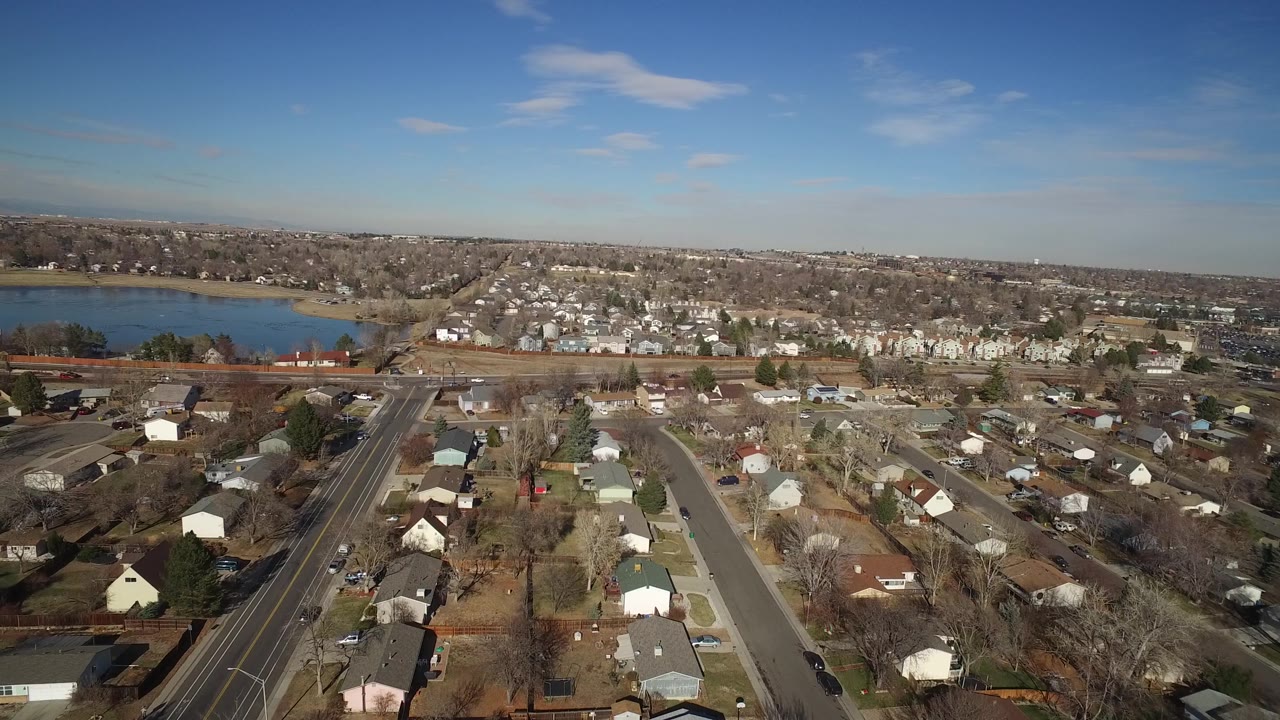 Aerial view across Hidden Lake, Colorado rooftops and tree-lined streets, with the lake in the left background and no visible people.