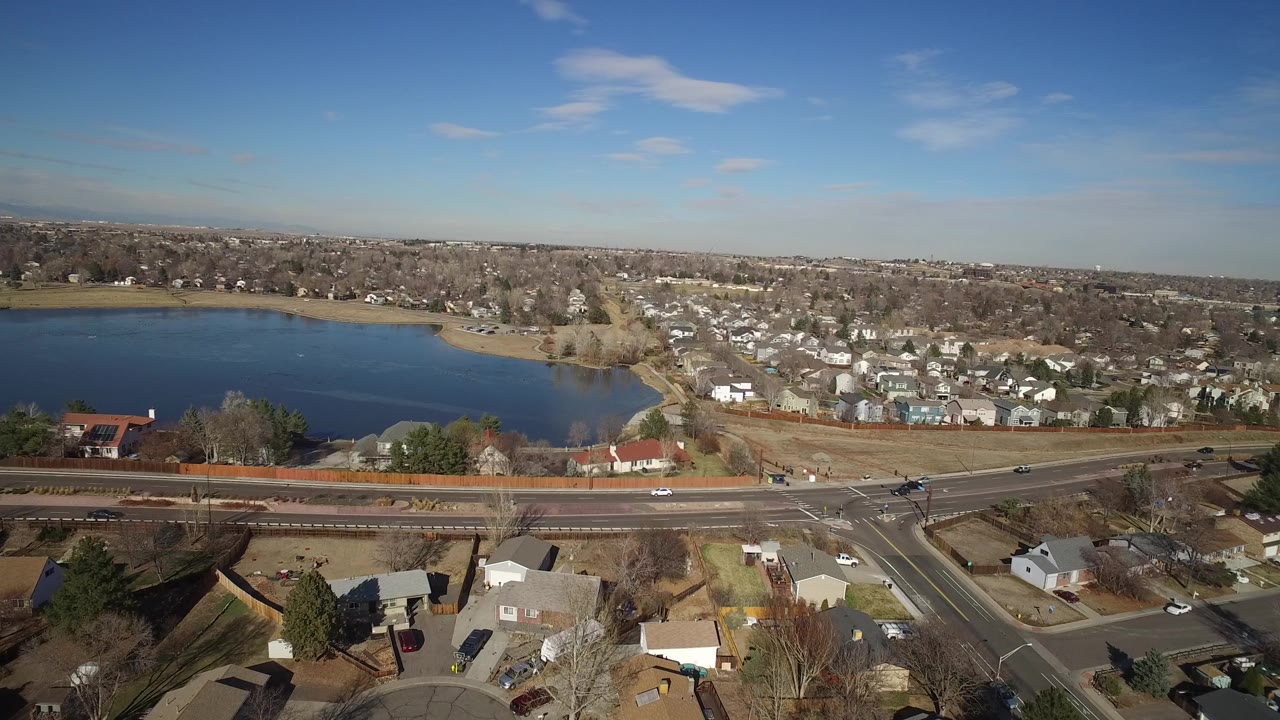 Aerial view of a lake, suburban homes, and a highway with cars.