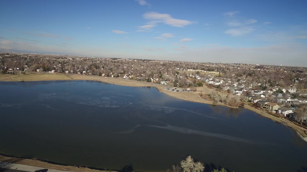 Aerial view of lake water, shoreline, and residential homes.