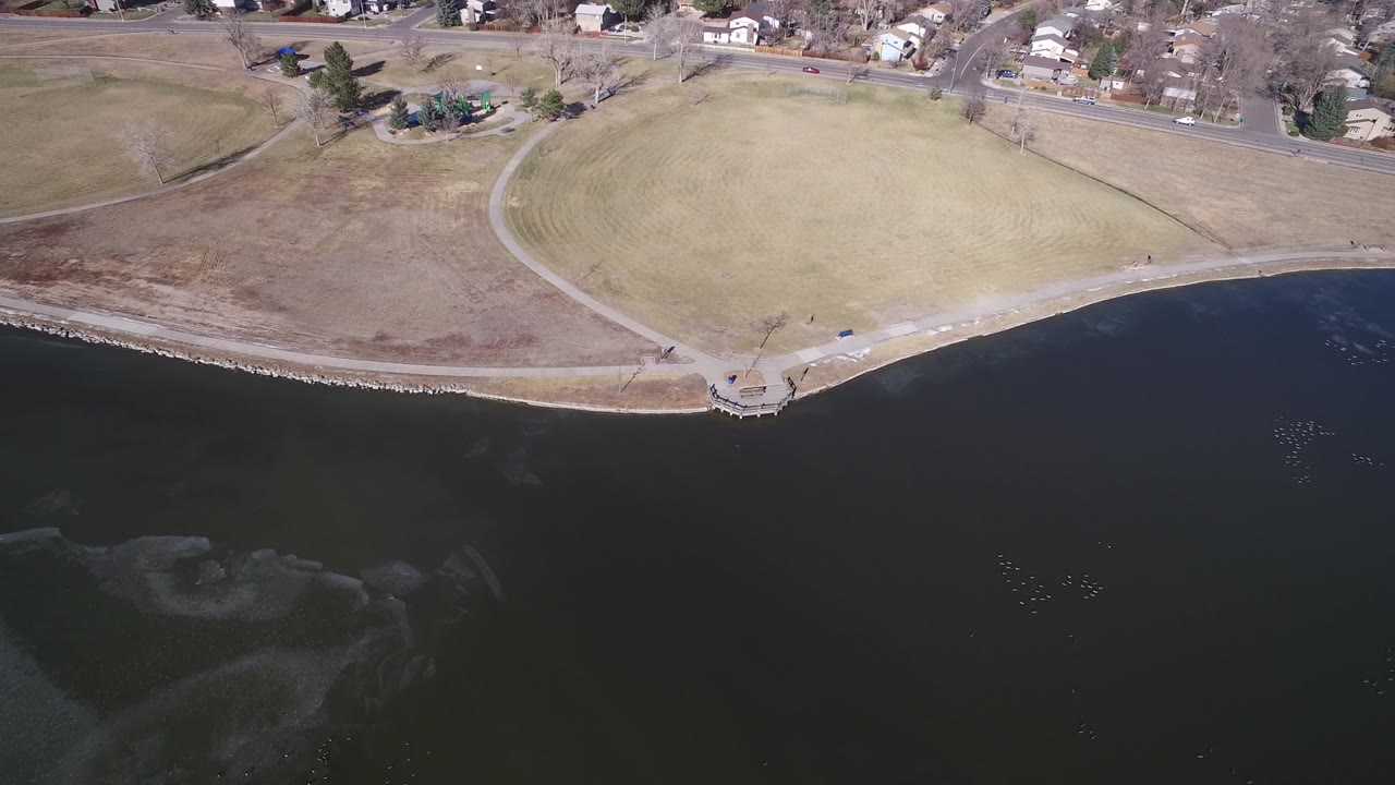 At 0:01, the Hidden Lake aerial view holds on dark water below a narrow shore, with the path loop and residential road clearer near the top and no visible people.