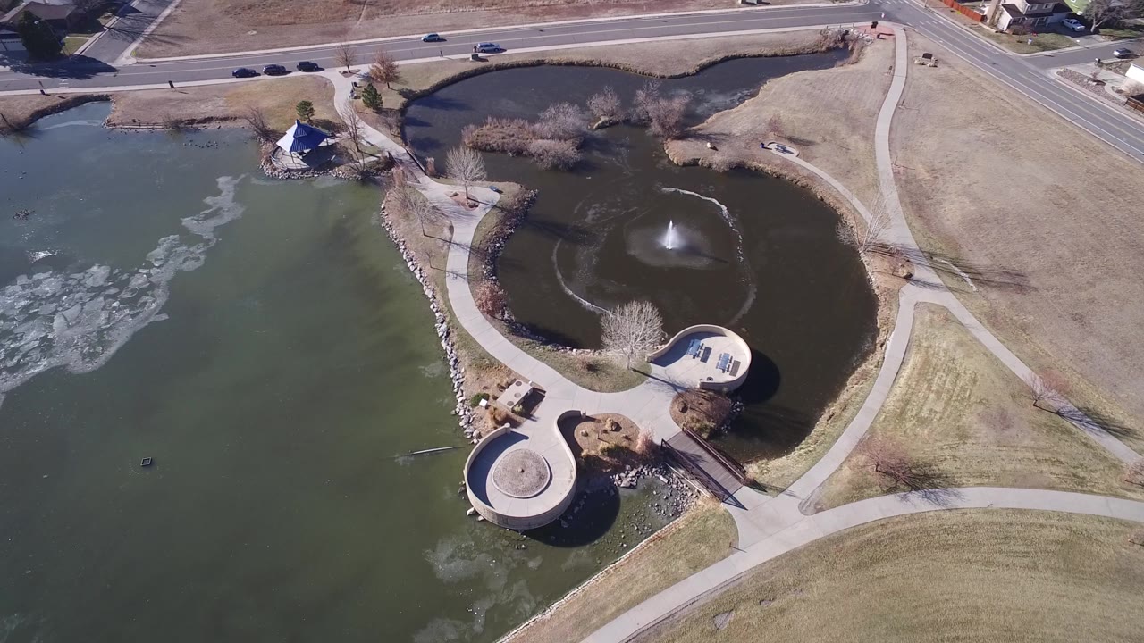 Hidden Lake, Colorado from above with the larger lake on the left, a dark fountain pond on the right, curved walkways, a roadside boundary, and no visible people.