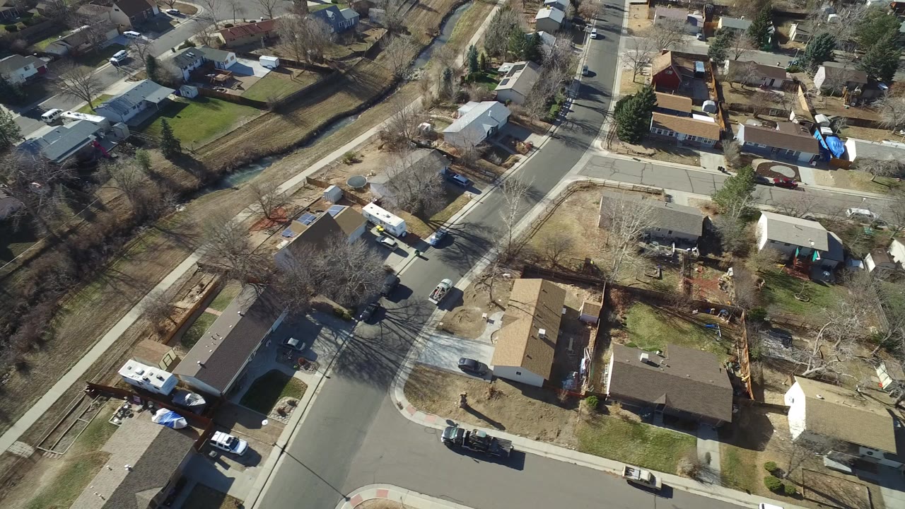 Aerial view over Hidden Lake, Colorado residential streets with single-story homes, parked cars, bare trees, and no visible people at the start of the clip.