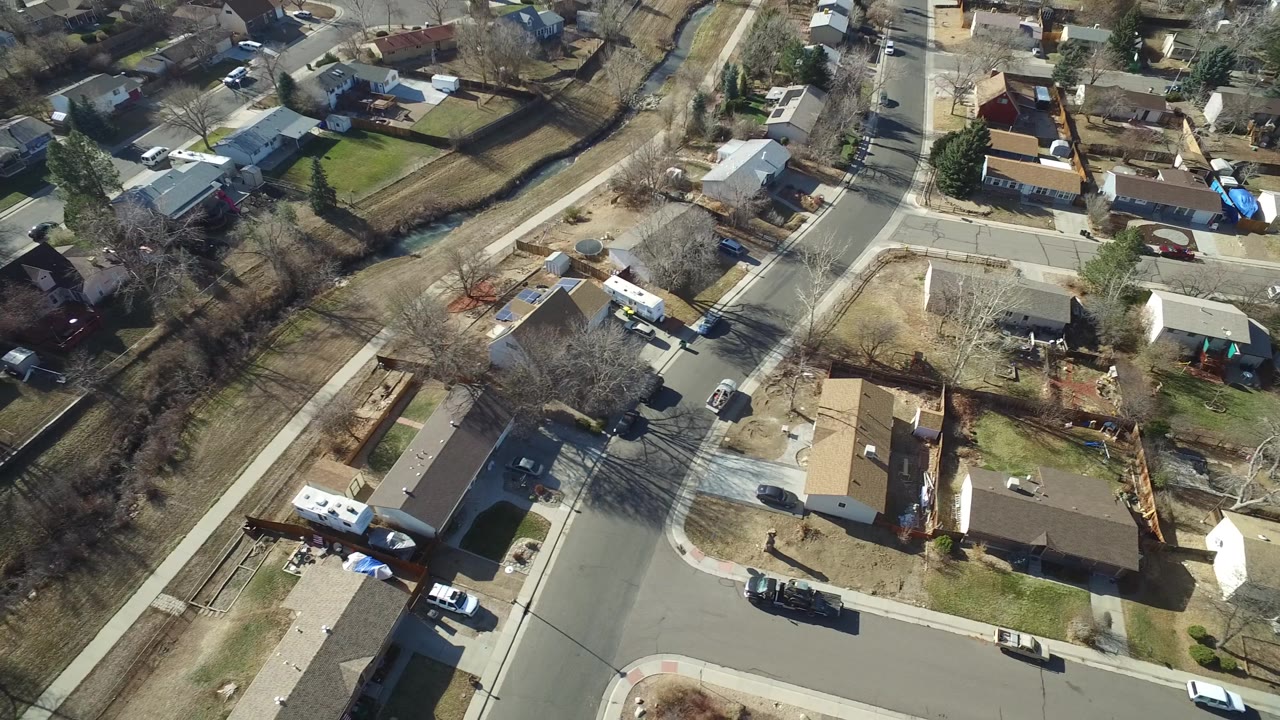 Drone-like overhead of parallel streets lined with homes and leafless trees.