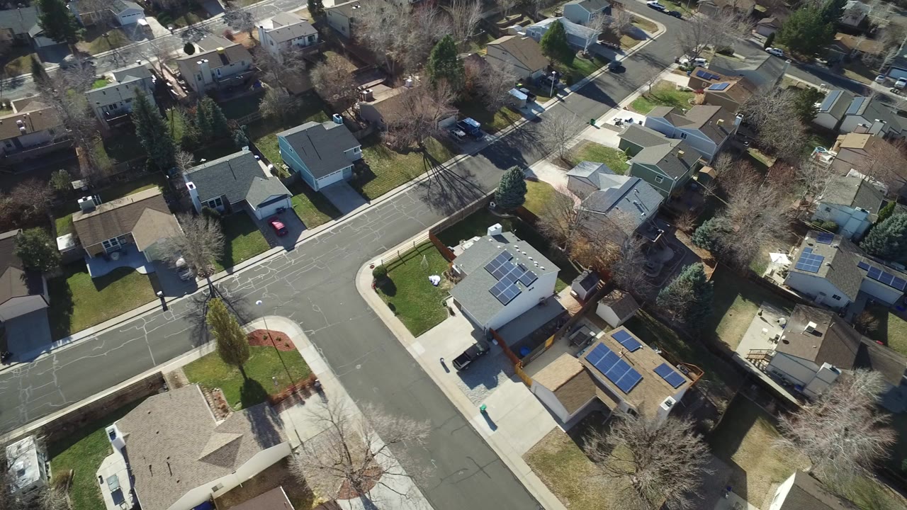 High overhead view of Hidden Lake, Colorado houses, lawns, driveways, parked cars, bare trees, and an angled street intersection with no visible people.