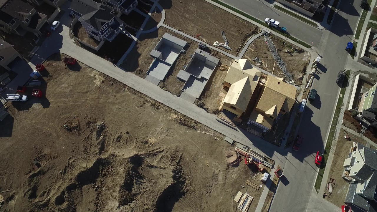 Overhead frame of Hidden Lake, Colorado with finished homes, framed construction, bare dirt lots, residential streets, parked vehicles, and no visible people.