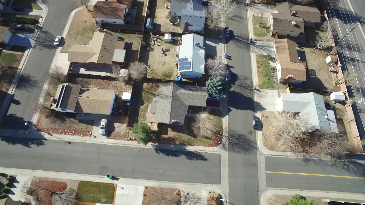 Overhead Hidden Lake, Colorado view with a wide street across the lower frame, clustered houses, a white-roofed home with solar panels, and no visible people.