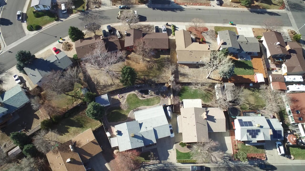 Overhead suburban houses and curved streets in bright daylight.