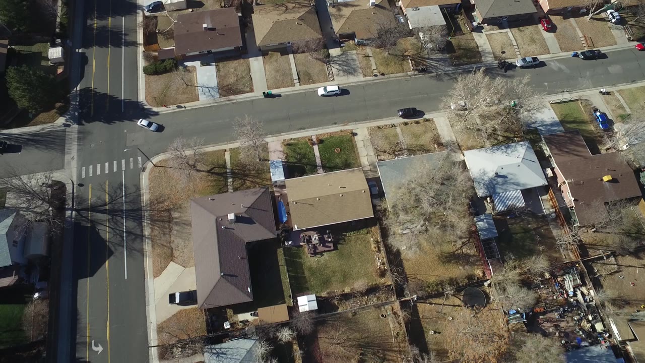 Drone-height view over Hidden Lake, Colorado backyards and roofs, with a cross street along the top edge and no visible people.