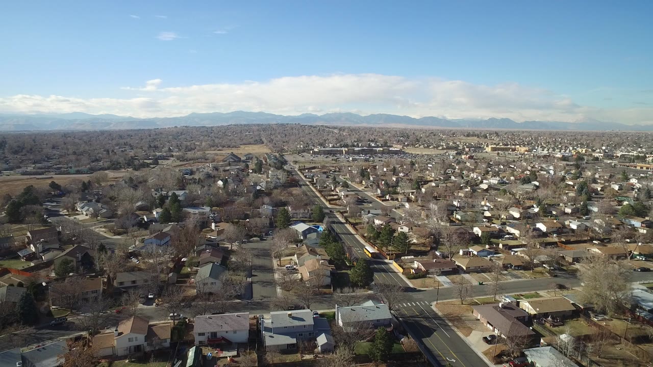 Aerial view over suburban homes and roads with mountains on the horizon