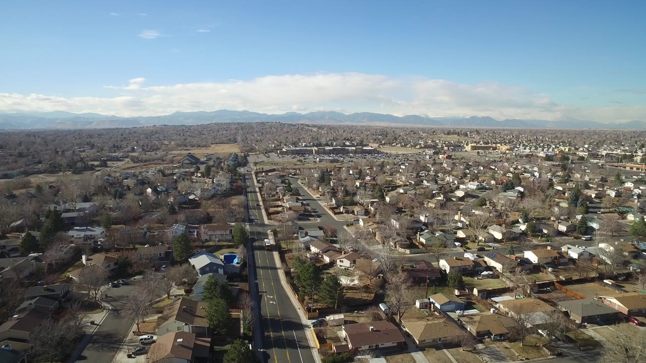 High aerial view of Hidden Lake, Colorado, looking across residential rooftops and intersecting streets toward low hills and mountains, with no visible people.