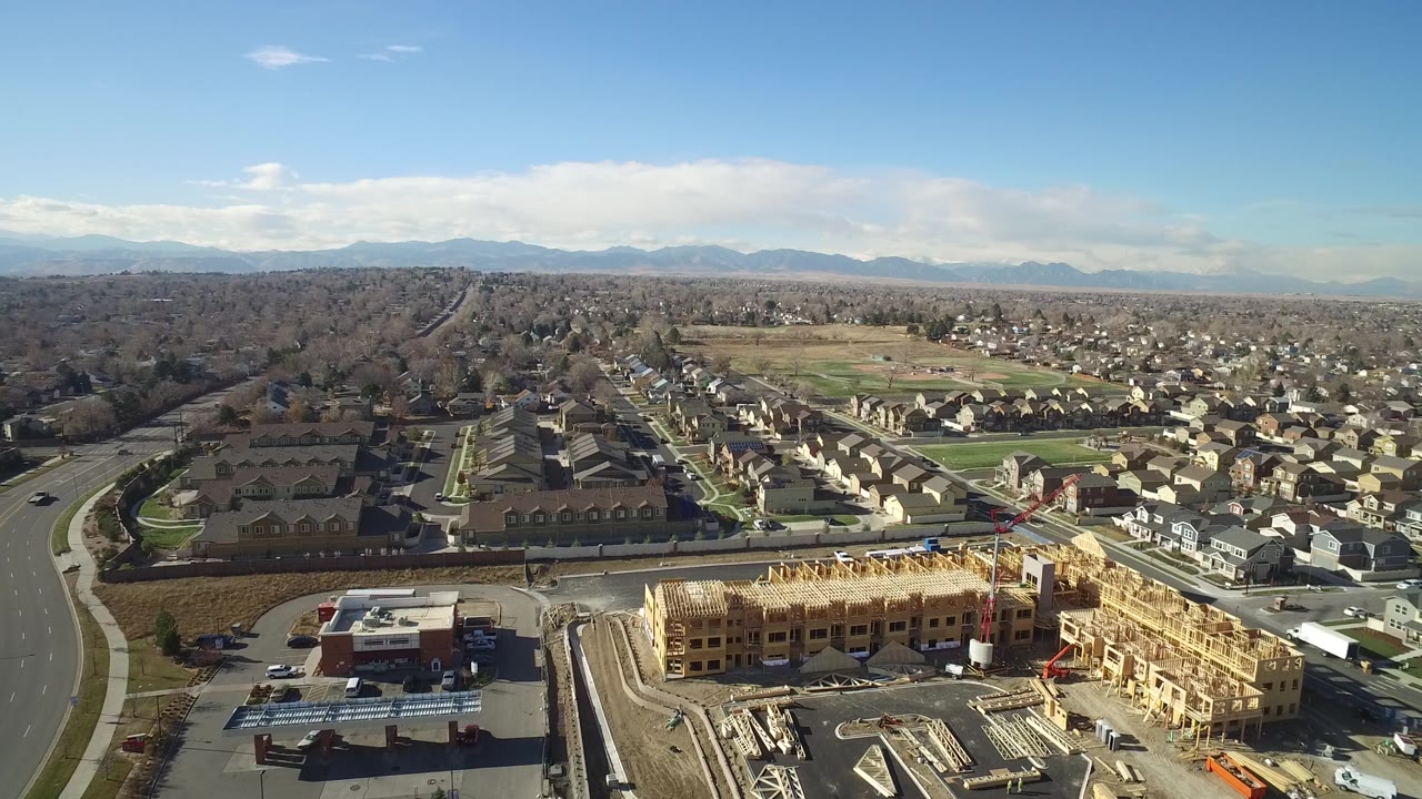 Aerial view in Hidden Lake, Colorado, showing the construction project lower center, residential streets running into the distance, open land, mountains, and no visible people.